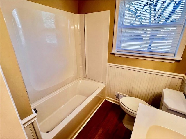 full bathroom featuring washtub / shower combination, hardwood / wood-style floors, vanity, and toilet