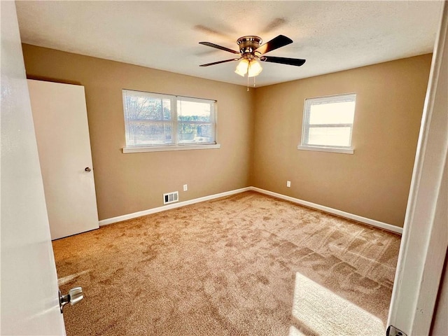 spare room featuring carpet flooring, ceiling fan, and a wealth of natural light