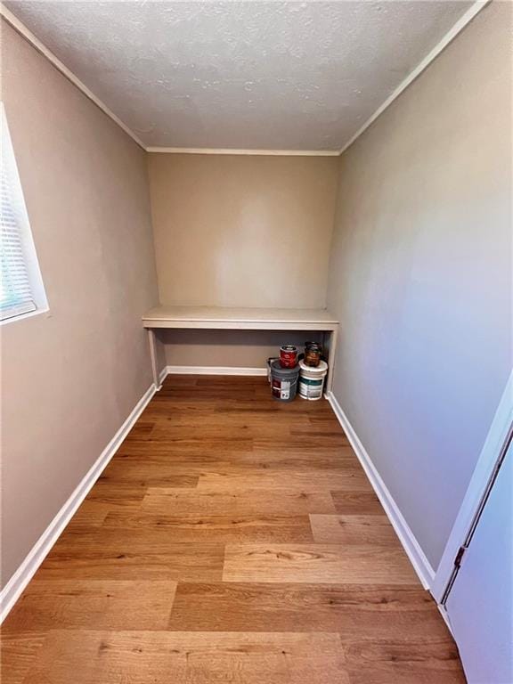 clothes washing area with crown molding, a textured ceiling, and light wood-type flooring