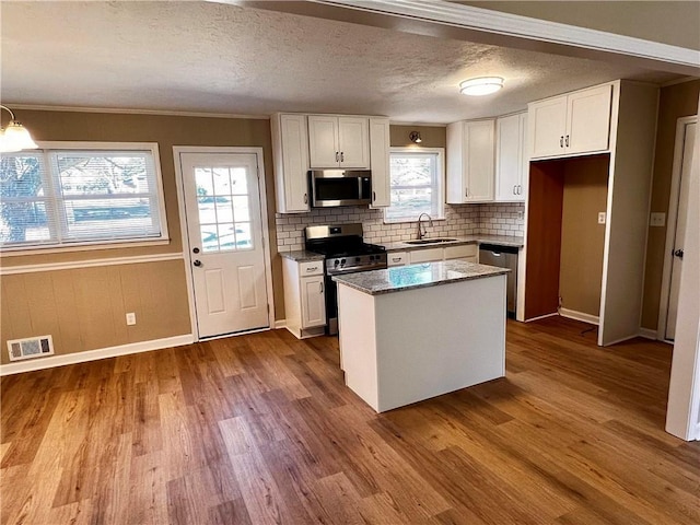 kitchen with white cabinets, a center island, sink, and stainless steel appliances