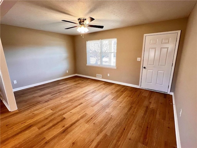 empty room featuring a textured ceiling, hardwood / wood-style flooring, and ceiling fan