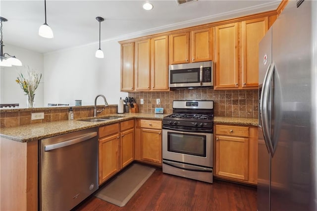 kitchen featuring kitchen peninsula, light stone counters, stainless steel appliances, sink, and pendant lighting