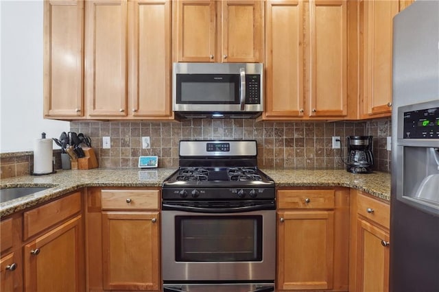 kitchen featuring decorative backsplash, light stone countertops, and appliances with stainless steel finishes