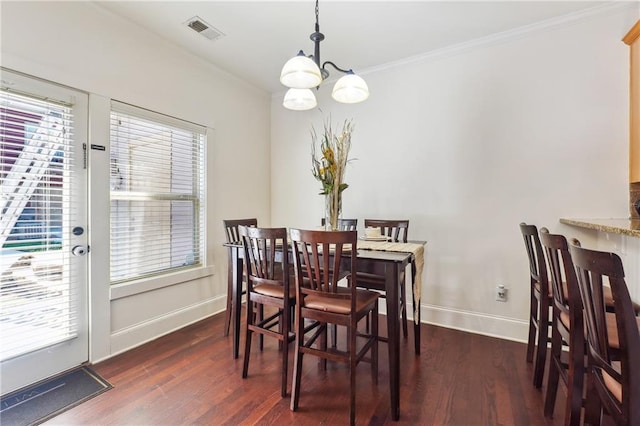 dining area featuring dark hardwood / wood-style floors, crown molding, and a chandelier