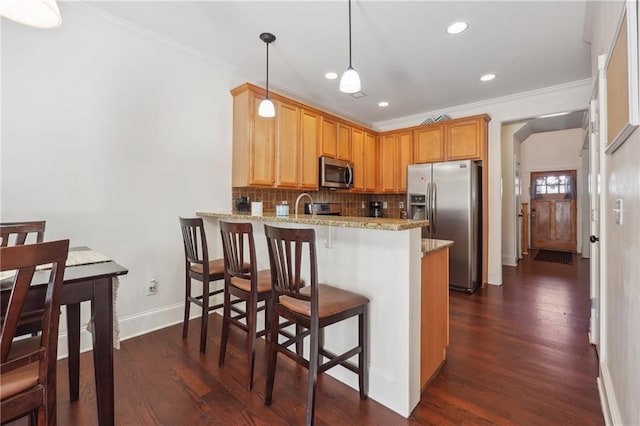 kitchen with pendant lighting, kitchen peninsula, ornamental molding, and appliances with stainless steel finishes