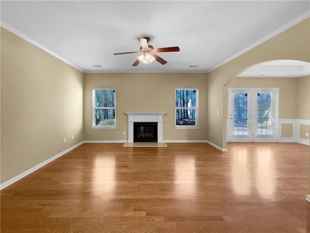 unfurnished living room featuring a fireplace with flush hearth, ornamental molding, and wood finished floors