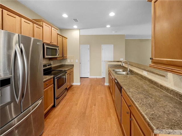 kitchen featuring visible vents, light wood-style flooring, appliances with stainless steel finishes, a sink, and backsplash