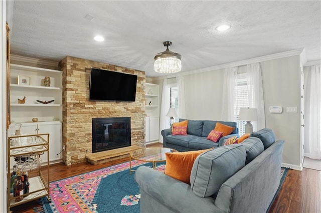 living area with baseboards, ornamental molding, a fireplace, wood finished floors, and a textured ceiling