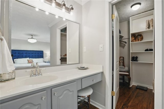 bathroom with wood finished floors, a textured ceiling, ensuite bath, and vanity