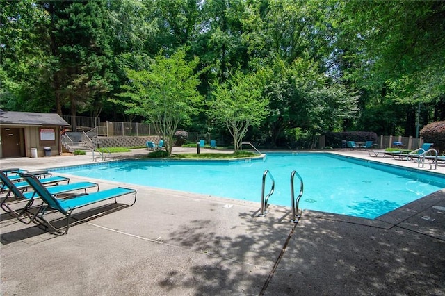 pool with a patio area and fence