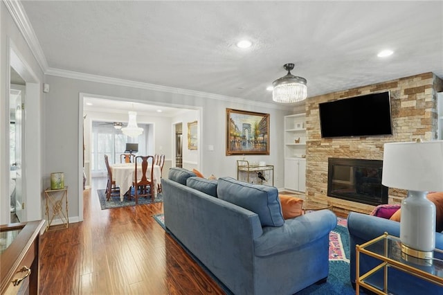 living area featuring built in shelves, crown molding, a fireplace, dark wood-style floors, and a textured ceiling