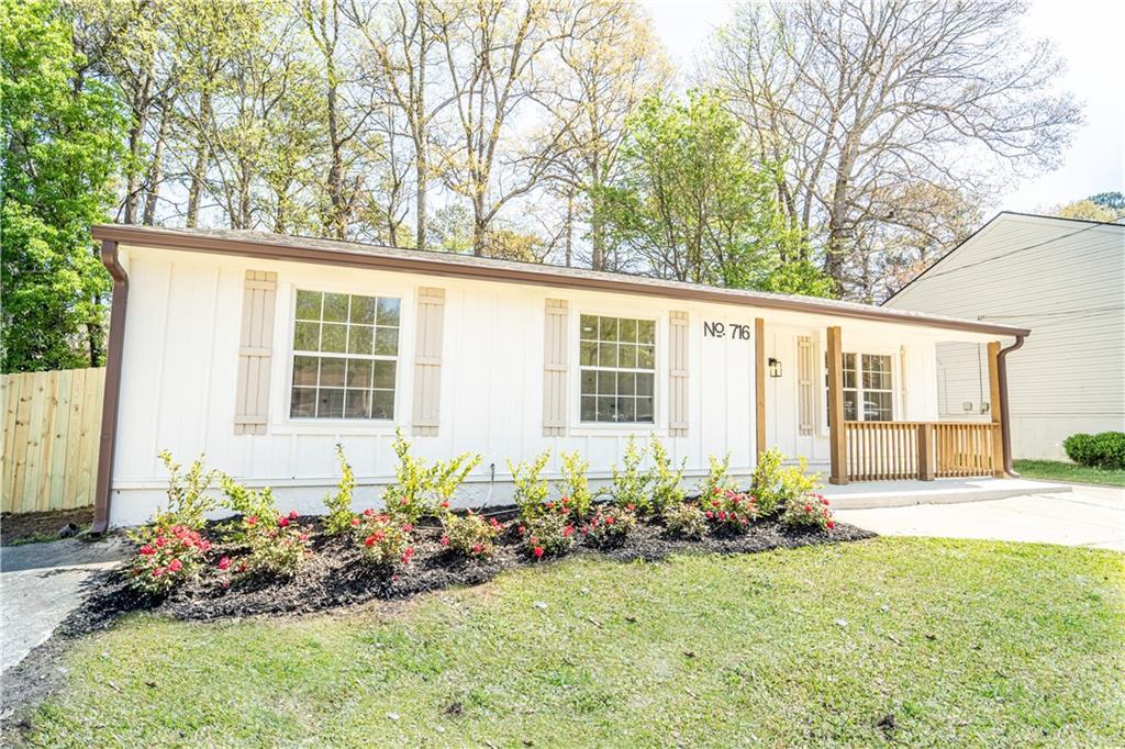view of front of house featuring fence, a front lawn, board and batten siding, and a porch