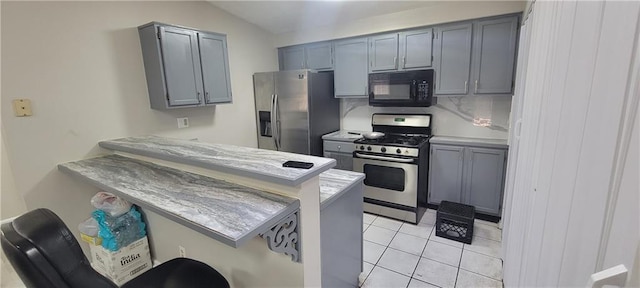 kitchen with a peninsula, light tile patterned flooring, gray cabinets, stainless steel appliances, and light countertops