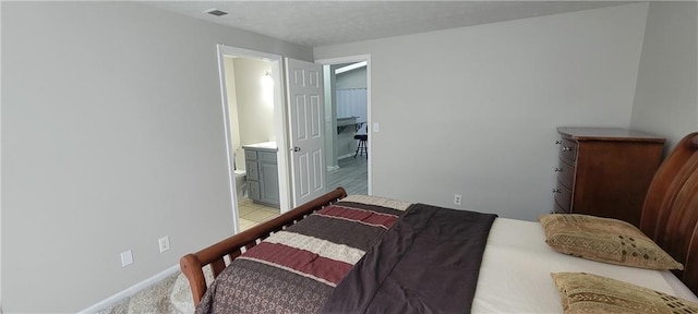 bedroom with visible vents, baseboards, and ensuite bathroom