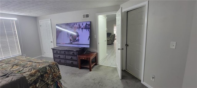 carpeted bedroom featuring visible vents, baseboards, and a textured ceiling