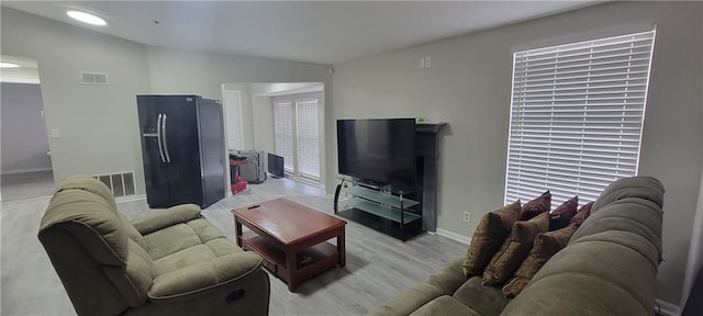 living area with baseboards, visible vents, and light wood-type flooring