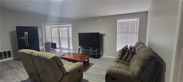 living area featuring a healthy amount of sunlight, wood finished floors, visible vents, and baseboards