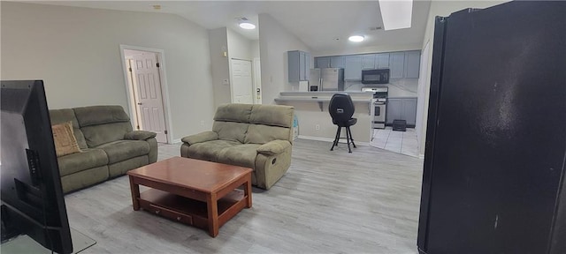 living area featuring baseboards, lofted ceiling, and light wood finished floors