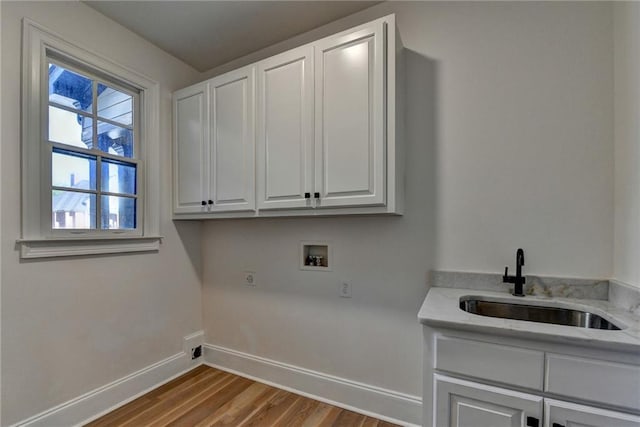 laundry area with wood finished floors, baseboards, hookup for a washing machine, a sink, and cabinet space