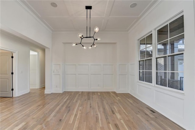 unfurnished dining area with an inviting chandelier, ornamental molding, visible vents, a decorative wall, and light wood-style flooring
