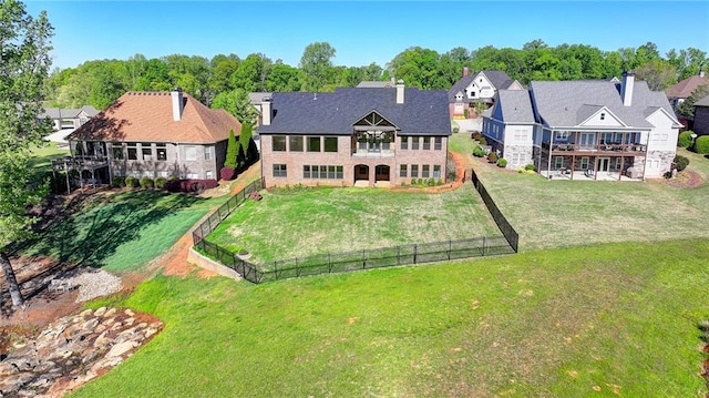 rear view of property with a fenced backyard, a balcony, a yard, and a residential view