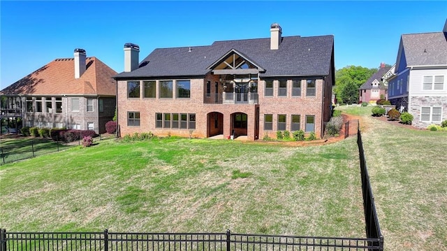 back of house featuring fence, a lawn, brick siding, and a balcony