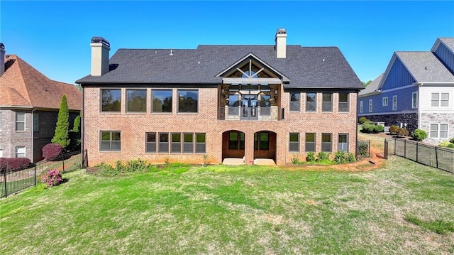 back of house featuring brick siding, a fenced backyard, a chimney, a balcony, and a lawn