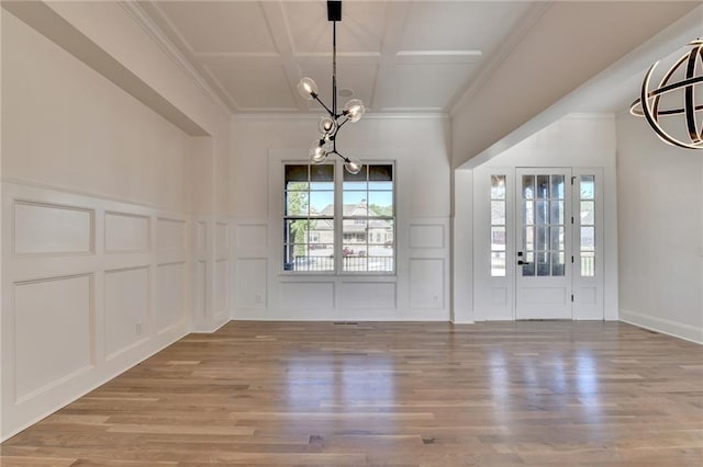 unfurnished dining area with wood finished floors, a decorative wall, and a notable chandelier