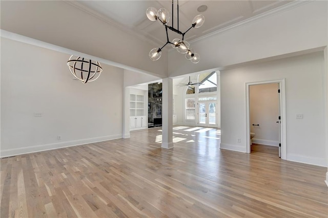 unfurnished dining area with baseboards, ornamental molding, french doors, and light wood-style flooring