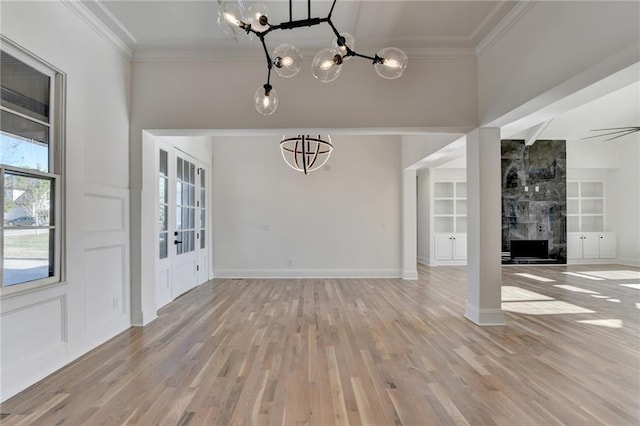 unfurnished living room with ornamental molding, light wood-style flooring, and a notable chandelier