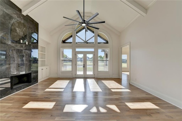 unfurnished living room with high vaulted ceiling, plenty of natural light, french doors, and beam ceiling