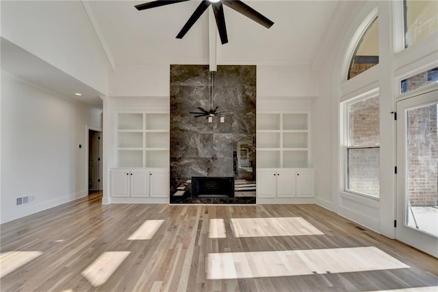 unfurnished living room featuring crown molding, a ceiling fan, and built in shelves