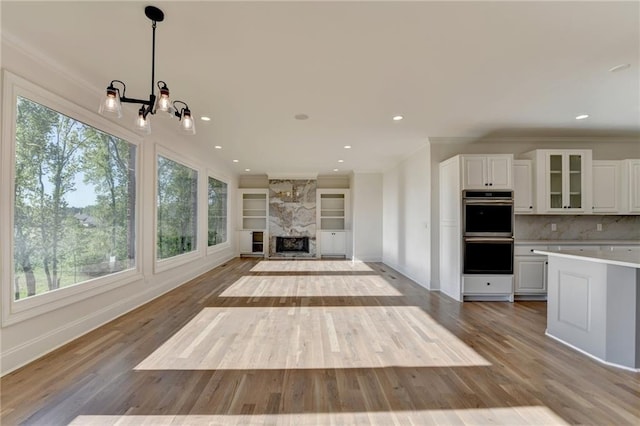 unfurnished living room featuring baseboards, light wood-style floors, crown molding, and a chandelier