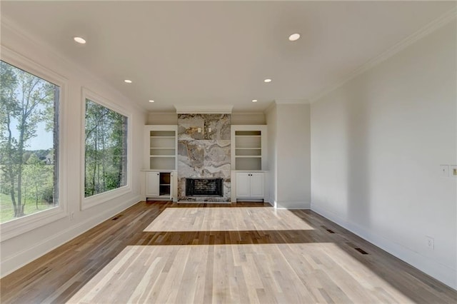 unfurnished living room with baseboards, wood finished floors, and a wealth of natural light