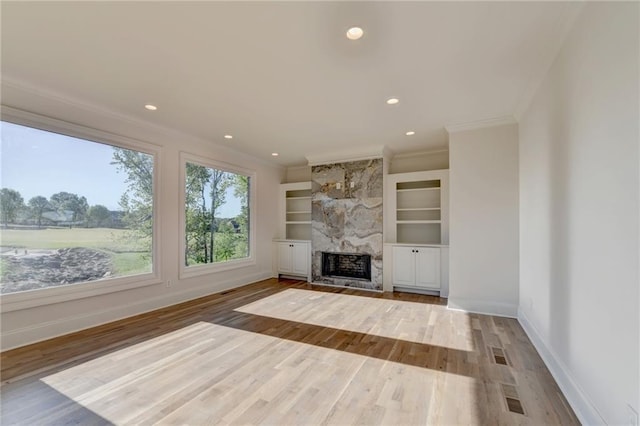 unfurnished living room featuring baseboards, ornamental molding, a fireplace, and wood finished floors