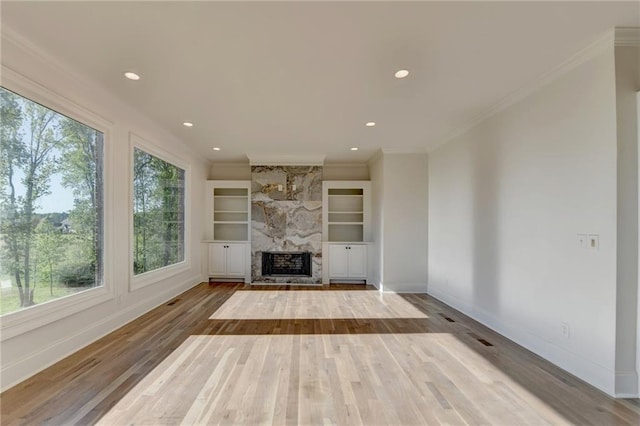 unfurnished living room with baseboards, recessed lighting, wood finished floors, and a large fireplace