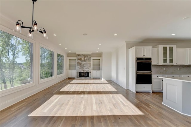 unfurnished living room featuring baseboards, ornamental molding, and light wood finished floors