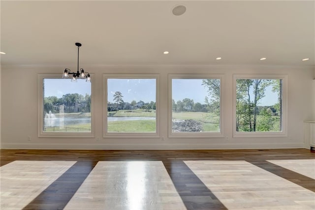unfurnished dining area with baseboards, ornamental molding, wood finished floors, and a notable chandelier
