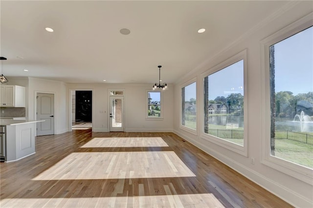 unfurnished dining area with an inviting chandelier, baseboards, and wood finished floors