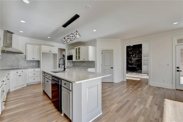 kitchen with wall chimney range hood, crown molding, a sink, white cabinetry, and decorative backsplash