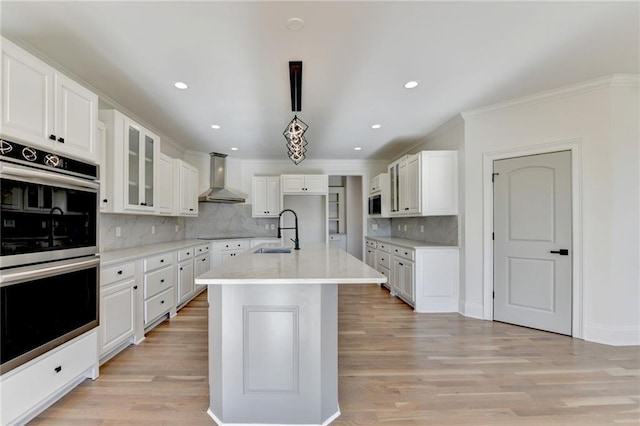 kitchen featuring ornamental molding, double oven, wall chimney exhaust hood, a sink, and backsplash