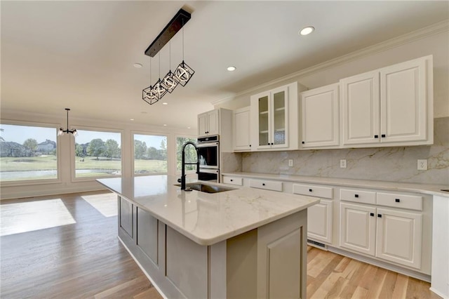 kitchen with double oven, light wood-style flooring, backsplash, and white cabinetry