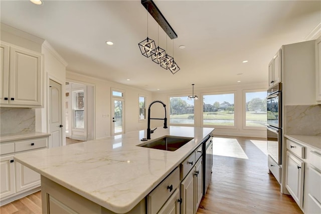 kitchen featuring a sink, appliances with stainless steel finishes, decorative backsplash, and light wood-style flooring