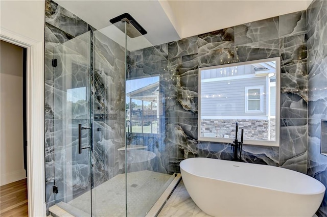 bathroom featuring a freestanding tub, tile walls, and a marble finish shower
