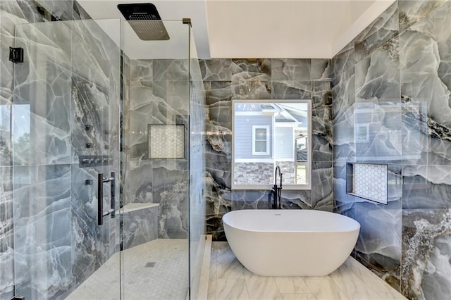 bathroom with a freestanding tub, tile walls, a marble finish shower, and marble finish floor