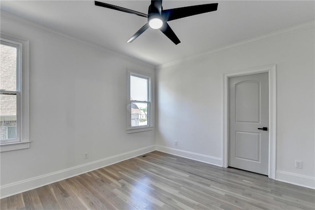 empty room featuring crown molding, baseboards, ceiling fan, and light wood-style floors
