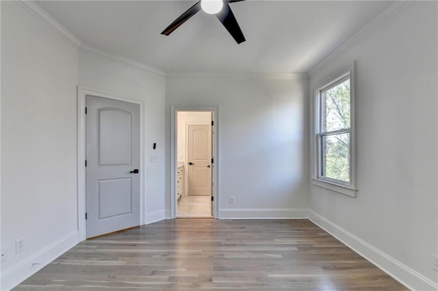 empty room with ceiling fan, ornamental molding, and wood finished floors