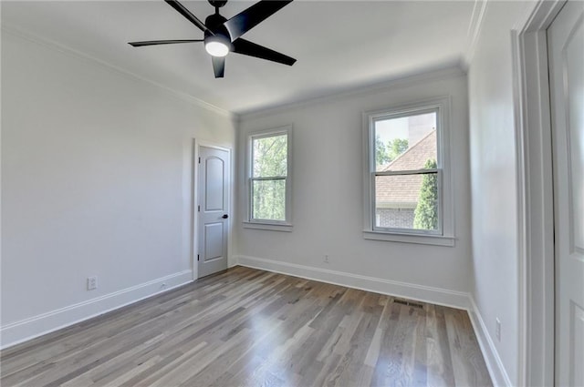 spare room with crown molding, visible vents, baseboards, a ceiling fan, and light wood finished floors