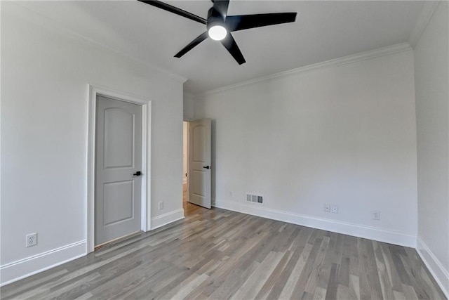 unfurnished bedroom featuring visible vents, ornamental molding, baseboards, and wood finished floors