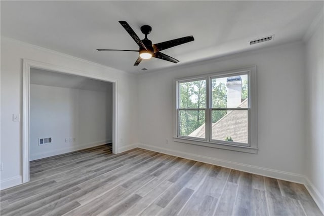 empty room with visible vents, a ceiling fan, light wood-style floors, and crown molding